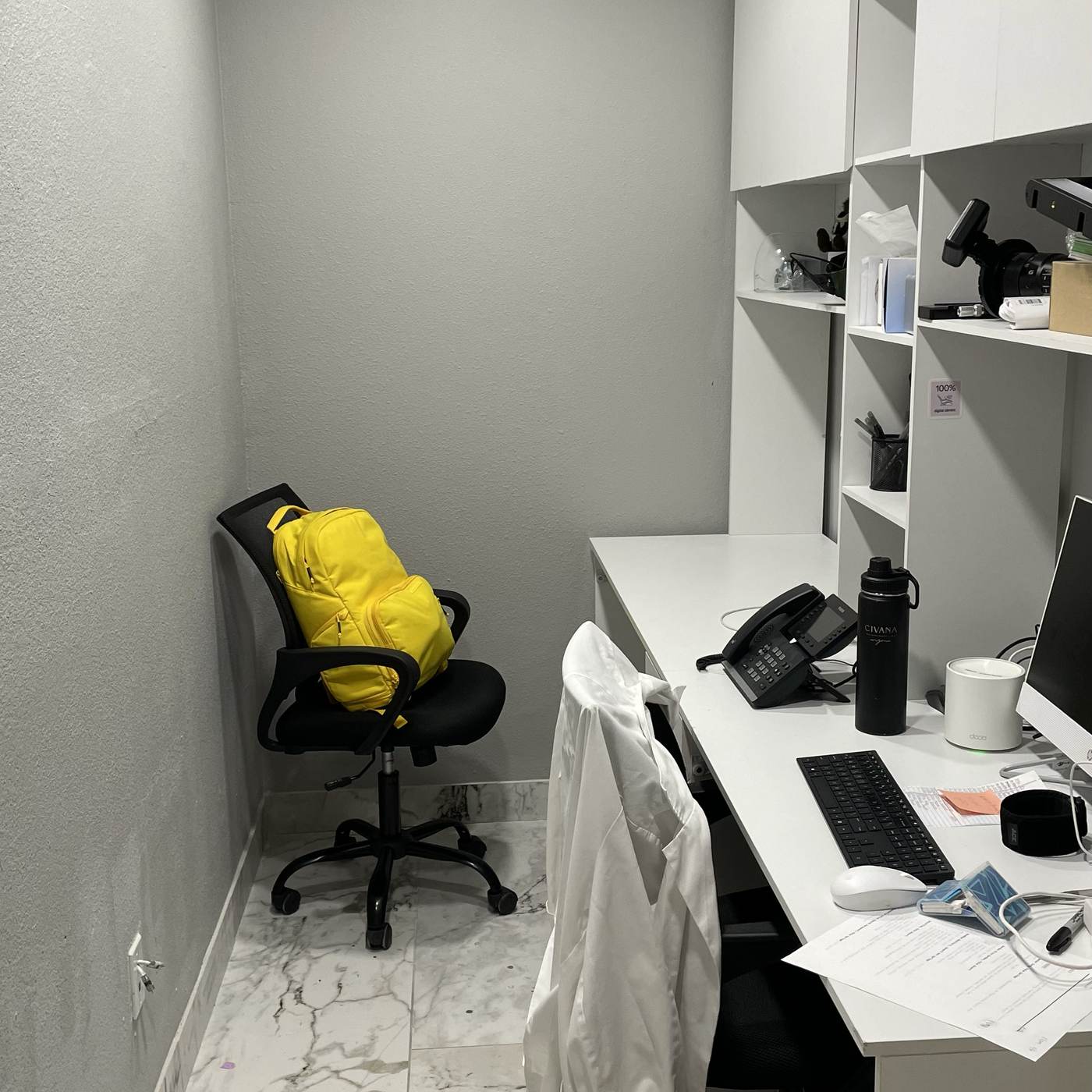 A cramped office corner with a chair, a desk, and built-in cabinets before the studio build